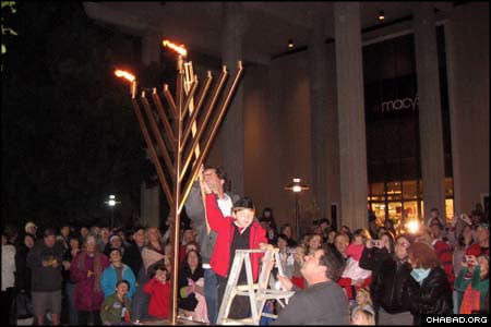 A child assists in the lighting of the Unity Menorah erected outside an area mall by Chabad-Lubavitch of S. Barbara. Mayor Marty Blum also assisted in the ceremony, as did community member Seth Olitzky, who lost his home in the fires that swept through Southern California last fall.