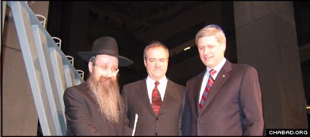 Rabbi Menachem Matusof, director of Chabad-Lubavitch of Alberta, stands with Calgary Mayor Dave Bronconnier and Canadian Prime Minister Stephen Harper beside a giant menorah at Calgary’s City Hall.