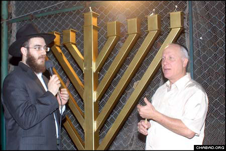Local businessman Asher Saddan kindles the Chanukah menorah.