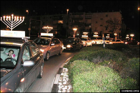 Scores of menorah-topped cars make their way through cities in Israel’s midsection as part of a Saturday night Chanukah parade.