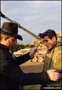 An Israeli soldier stationed on the Gazan border dons tefillin with a Chabad-Lubavitch rabbi on Tuesday. (Photo: Israelhomefront.org)