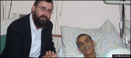 Rabbi Menachem Kutner of Chabad’s Terror Victims Project visits with an injured Israeli soldier at Beilinson Hospital in Petach Tikva.