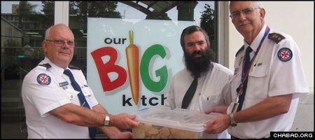 Superintendents Howard McIlvanie, left, and Phil Wilson of the Ambulance Service of New South Wales take delivery of emergency food supplies from Rabbi Dovid Slavin, director of the Yeshiva Centre’s Our Big Kitchen.