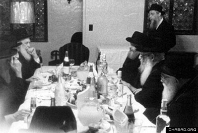 At the festive meal following the fast of Yom Kippur, the Rebbe is sitting on the far right of the picture, his brother-in-law, Rabbi Shmaryahu Gurary, on the far left. The empty space at the head of the table is where Rabbi Yosef Yitzchak, the sixth Chabad Rebbe, would sit during his lifetime. (Photo: Agudas Chasidei Chabad Library)