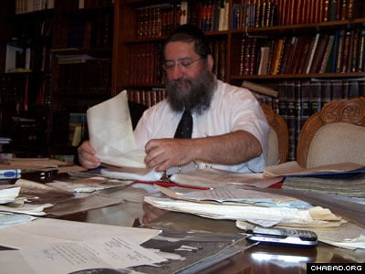 Rabbi Dovid Cohen with the letters his father-in-law, Rabbi Zeev Greenglass, received from the Rebbe. In the left corner is a letter from the Rebbe with blessings for a sweet new year.