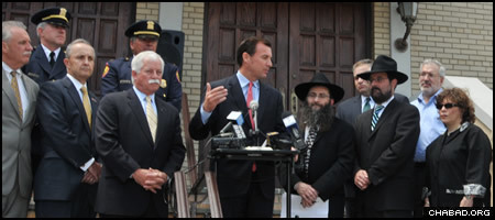 With Rabbi Anchelle Perl at his side, Nassau County Executive Thomas Suozzi addresses a rally in front of Congregation Beth Sholom Chabad in Mineola, N.Y., in response to the discovery of two swastikas spray-painted on the front of the synagogue’s entrance.