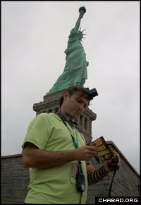 A Jewish man from Venezuela dons tefillin at the foot of the Statue of Liberty.