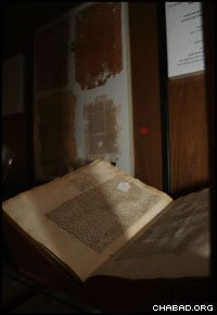 A book on Jewish law bearing the notes of the famed 18th-century decisor Rabbi Akiva Eiger sits in front of salvaged pages from early editions of the Talmud.