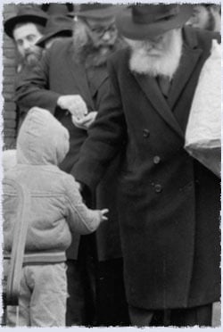 The Rebbe exiting 770 on that morning, distributing coins to the children to give to charity.