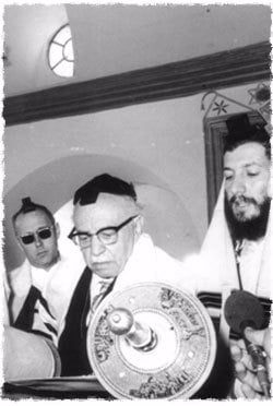 Mr. Kalms (left) at the reading of the Torah, in the &quot;Tzemach Tzedek Shul,&quot; as President of Israel Zalman Shazar makes the blessing on the Torah.