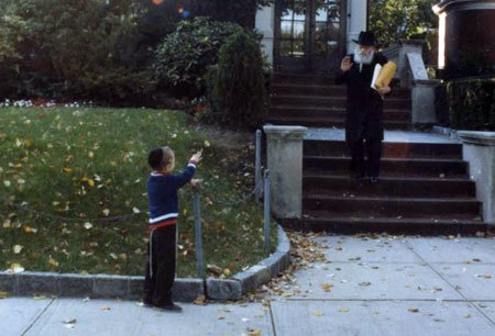 The Rebbe greets a small child as he leaves his home on the way to his office at Lubavitch World Headquarters (Photo: Shafran Family/Lubavitch Archives).