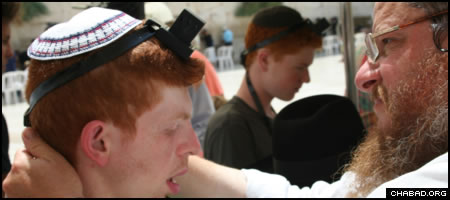 A participant on a summer Birthright Israel trip for people with special needs dons the Jewish prayer boxes known as tefillin at the Western Wall.