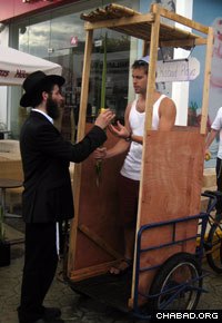 A visiting rabbinical student helps a Jewish tourist make a blessing in a mobile sukkah during the Jewish holiday of Sukkot.