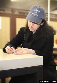 Judy Federbush composes her thoughts as she writes a note to be read at the Rebbe’s resting place.