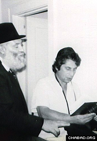 Rabbi Zalman Kazen helps a Jewish man don the prayer boxes known as tefillin.