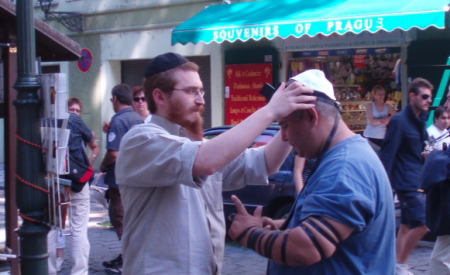 A roving rabbi helping a Jew don tefillin on the streets of Old Prague a number of summers ago.
