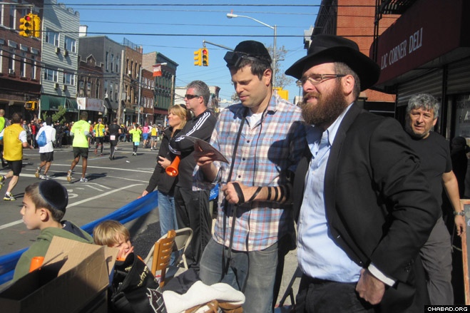 Chabad-Lubavitch of Long Island City director Rabbi Zev Wineberg helps a Jewish spectator don the prayer boxes known as tefillin during Sunday’s annual New York City Marathon.