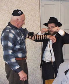 Margolin putting on tefillin with a Gaisin Jew a few hours before Pesach.