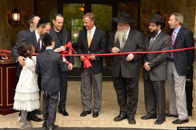 Rabbi Yitzchok Tiechtel helps his children Levi and Chana present the ceremonial ribbon cutting scissors to Tennessee Gov. Bill Haslam, who joined Rabbi Moshe Kotlarsky, vice chairman of Merkos L'Inyonei Chinuch, the education arm of Chabad-Lubavitch, for the grand opening of the Genesis Campus for Jewish Life.