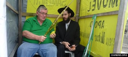 Chabad-Lubavitch Rabbi Arieh Raichman helps a local Jew make a blessing on a lulav and etrog inside of a mobile sukkah in Manaus, Brazil.
