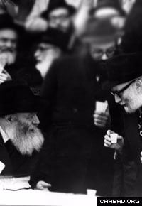 Rabbi Yosef Wineberg, right, speaks with the Rebbe, Rabbi Menachem M. Schneerson, of righteous memory, at a public Chasidic gathering.