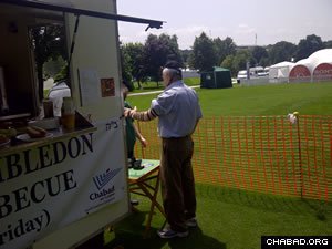 A Wimbledon spectator takes a prayer break alongside a kosher food truck operated by the local Chabad House.