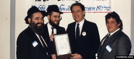 Rabbis Zalman Lipsker of Philadelphia and Yisroel Rosenfeld of Pittsburgh, Pa., present a plaque to Sen. Arlen Specter at the 1987 celebration of Education Day, USA, and the commemoration of the 85th birthday of the Rebbe, Rabbi Menachem M. Schneerson, of righteous memory. (Photo: Lubavitch Archives)