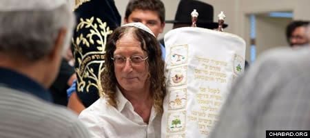 Stephen Cipes carries the newly written Torah scroll he donated to the Chabad center in Kelowna, British Columbia, Canada.