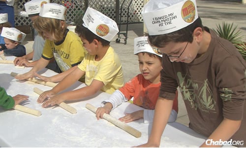 Kids keep busy at an outdoor model matzah bakery event. The area west of Route 441 has seen a huge boom in housing, which has attracted families there.