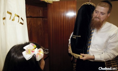 Rabbi Yitzchok Schmukler, co-director of Chabad of the Bay Area with his wife, Malky, stands in front of the aron kodesh, or Holy Ark, with the Torah he received on long-term loan, as his daughter Mushkie looks on. (Photo: KEVIN M. COX/The Galveston County Daily News