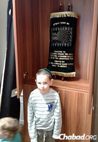 Mendy Kaminetzky, 6, stands in front of the Torah sent to Chabad-Lubavitch of Serbia, in Belgrade, co-directed by Yehoshua and Miri Kaminetzky.