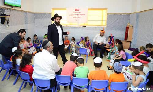 On Thursday, Rabbi Asher Pizem of Chabad of Sderot helped entertain children stuck inside all day because of the situation. Seated in front of him is Rabbi Prus of Kfar Chabad, Israel, and to Pizem&#39;s right, with the orange balloon hat, is CTVP staffer Rabbi Yossi Swerdlov. (Photo: Meir Alfasi)