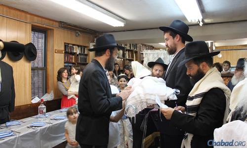 Rabbi Moshe Rosenberg giving the Birchas Kohanim (the priestly blessing), and Rabbi Moshe Berghoff holding the baby; to the right is Rabbi Yankee Teitelbaum.