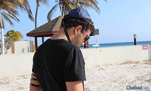 At a Lag BaOmer beach barbecue, resident Jon Atias performs the mitzvah of wrapping tefillin.