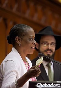 State Treasurer Denise Nappier gives a dollar to charity, as Rabbi Shaya Gopin of the Chabad House of Greater Hartford, looks on.