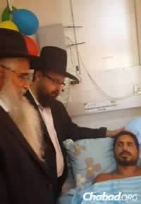 Rabbi Amitai Yemini, director of the Chabad Israel Center in Los Angeles, left, and Rabbi Menachem Kutner, director of the Chabad Terror Victims Project, visited with Mordechai Yemin, a wounded soldier. (Photo: CTVP)