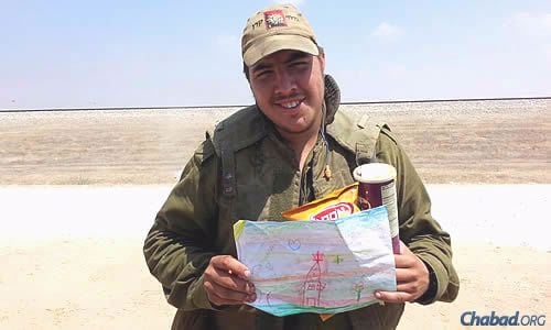 An IDF soldier displays a child&#39;s message, tucked into packages of food.