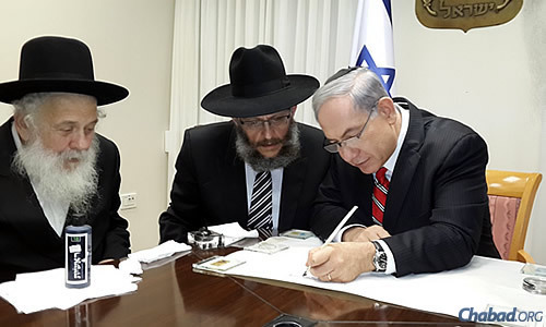 Netanyahu writes a letter in the first verse of the Torah using a special quill pen.