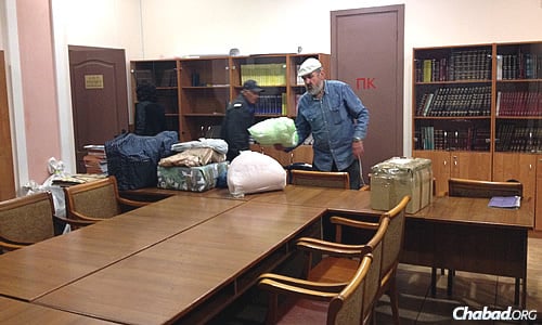 Volunteers bring the newly arrived supplies into the community&#39;s temporary synagogue space in Kiev. (Photo: Dovid Margolin)