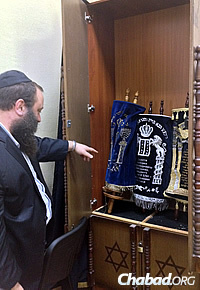 Rabbi Levi Raices, who heads the Yeshiva Ketana in Kharkov, points to Torah scrolls that were recently brought out of Lugansk and are being held at the yeshivah for safekeeping.