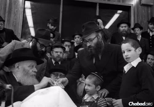 Rabbi Azimov receiving a dollar and a blessing from the Lubavitcher Rebbe. (Photo: JEM/The Living Archive)