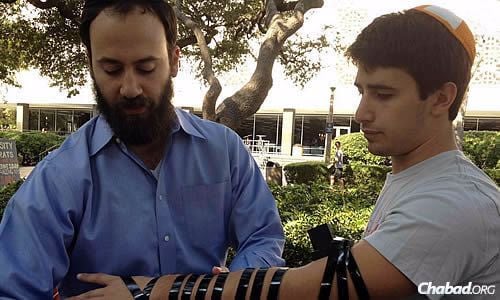 Johnson helps a student wrap tefillin on campus.