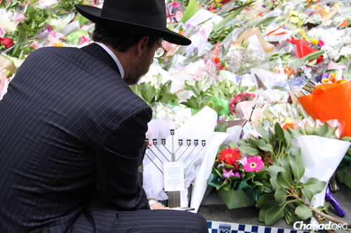 Rabbi Levi Wolf, chief minister and spiritual head of Sydney’s Central Synagogue, places a menorah among a sea of flowers at Martin Place, site of a recent terror attack.