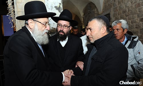 Rabbi Aryeh Stern, Ashkenazi chief rabbi of Jerusalem, greets a family member who came to a Chanukah menorah-lighting ceremony in honor of Israeli Defense Forces soldiers killed in the summer war with Hamas in Gaza. Next to them is Rabbi Menachem Kutner, director of the Chabad Terror Victims Project, which invited the families. (Photo: Mendy Hechtman)