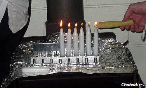The shamash candle used to kindle the other flames on the menorah is often made by campers, like this beeswax one.