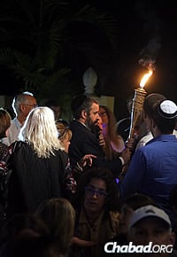 Harlig hands a torch to David Mermelstein, a longtime friend of Sotloff&#39;s grandparents, who walked it through a crowd of hundreds. (Photo: Marta Villalba)