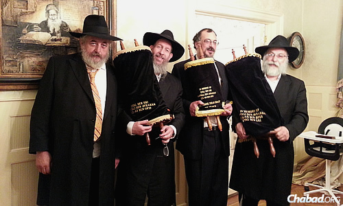 These Torahs were commissioned in honor of the three Israeli teenage boys abducted and killed by Palestinians in June 2014. Holding them, from left, are Yankel Yankelowitz; Bentzion Chanowitz, who runs the Torah Gemach, a project of Merkos Suite 302; Yerachmiel Paskin; and sofer (Torah scribe) Rabbi Daniel Dovid Dahan.