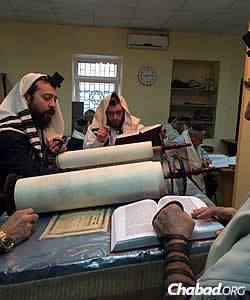Chabad Rabbi Mendel Cohen, the city's rabbi, reads Torah in Mariupol's synagogue. Rabbi Aaron Kaganovsky, who has taken over some of the shul's daily operations, is to his right.
