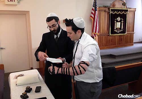 Rabbi Yehuda Ceitlin, outreach director of Chabad Lubavitch of Tucson and associate director of Congregation Young Israel-Chabad, wraps tefillin with Justin Schecker, a reporter for KGUN 9 television news.