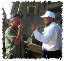 Rabbi Aaron Prus helps a soldier with tefillin.